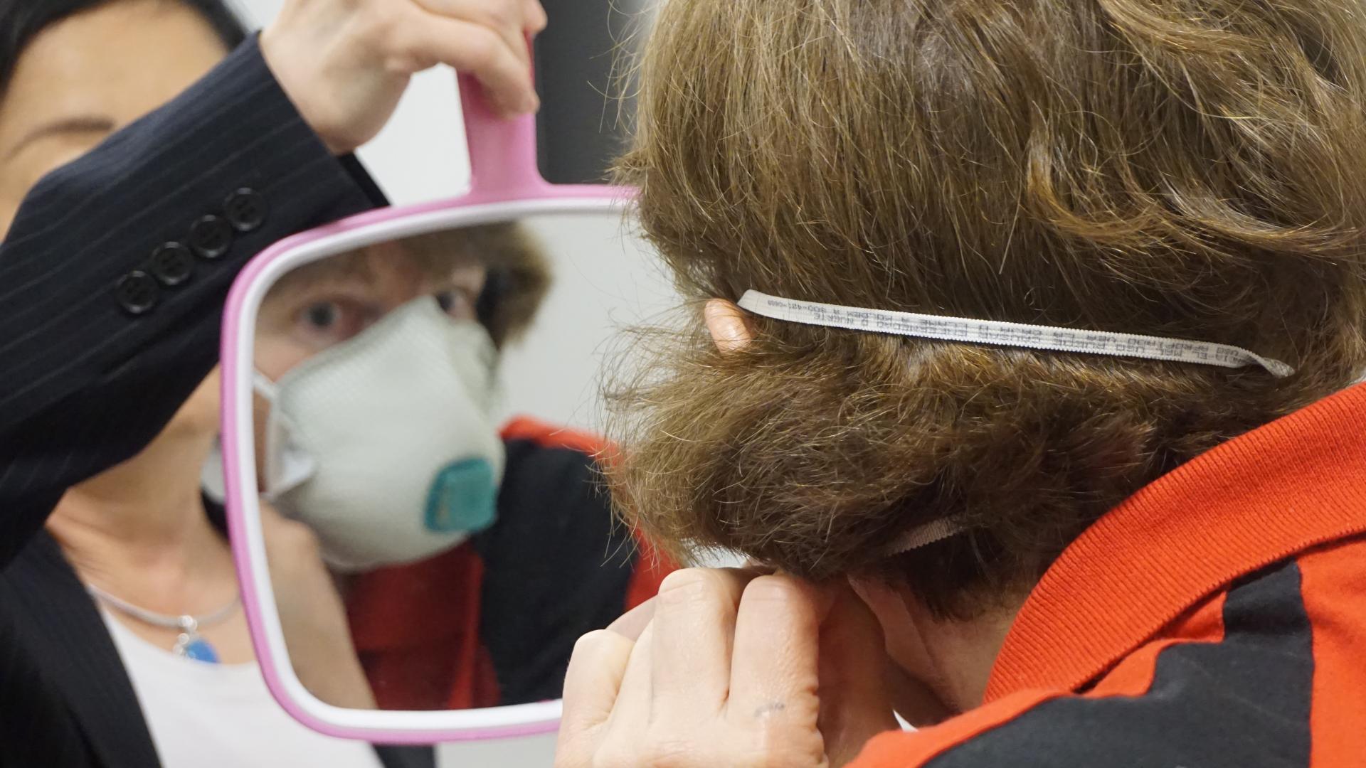 Applicator looks at how a respirator fits in the mirror